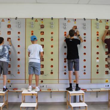 Schüler arbeiten an einer elektrischen Schalttafel in einem Schulungsraum in Österreich.