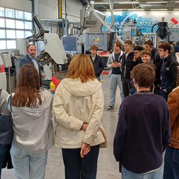 Lehrer erklärt Schülern Maschinen in Werkstatt in Österreich.