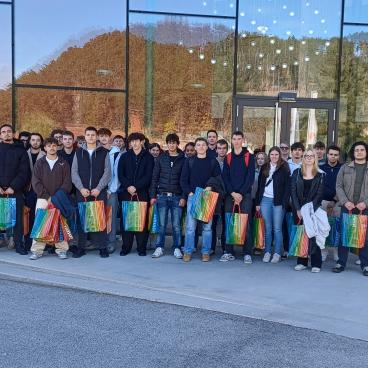Gruppe von Jugendlichen mit bunten Taschen vor modernem Gebäude in Österreich