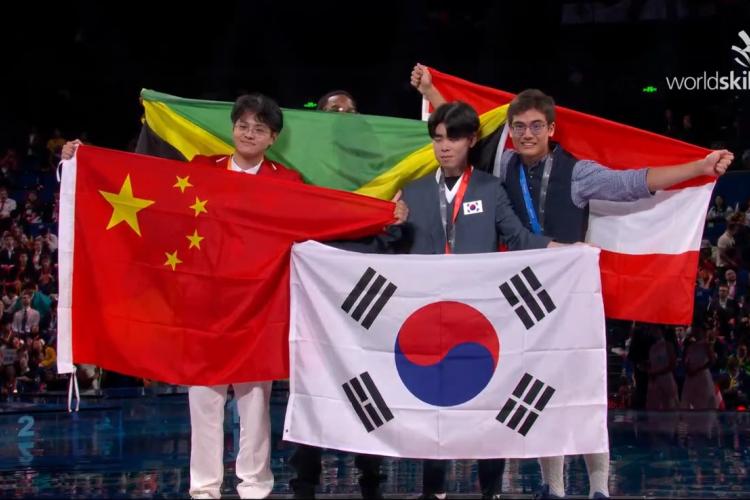 Südkoreanischer Teilnehmer mit Flagge, chinesischer Teilnehmer mit Flagge und ein weiterer Teilnehmer mit Flagge.