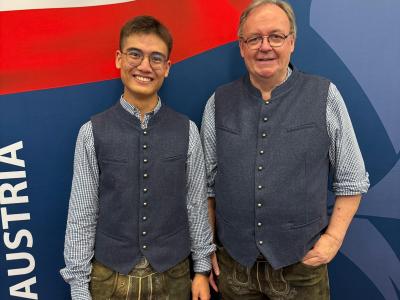 Zwei Männer im Trachtenlook vor dem Schriftzug AUSTRIA